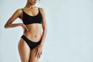 Woman poses in black swimsuit, showing off a toned, slender body after body contouring